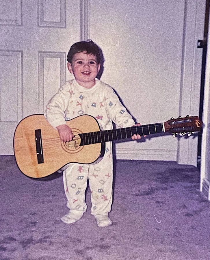Yan tout petit, en pyjama, tient une guitare plus grande que lui